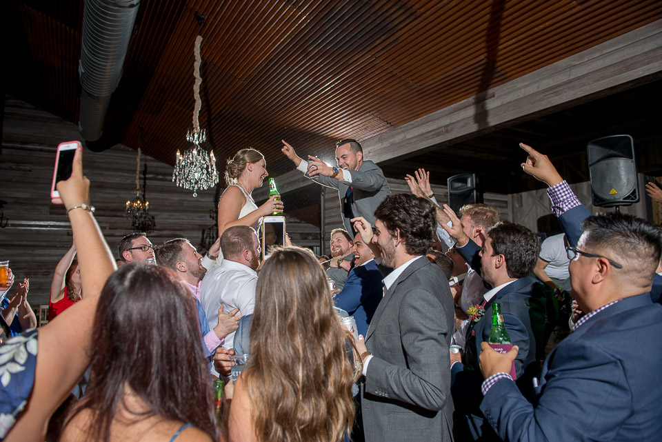 bride and groom are lifted in the air by their wedding guests