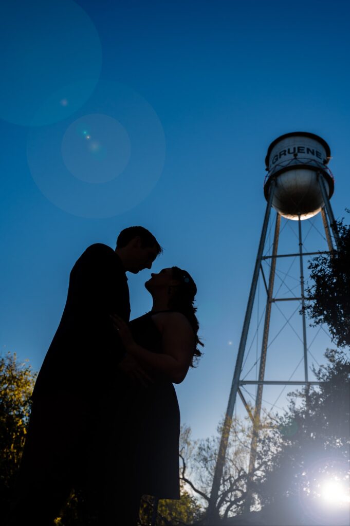 a silhouetted couple standing in front of the gruene water tower in gruene, texas by San Antonio TX Wedding Photographer Tammy Blalock